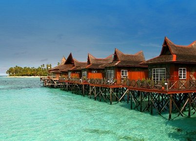 Over-the-water chalets on stilts above clear shallow water at Mabul Water Bungalows