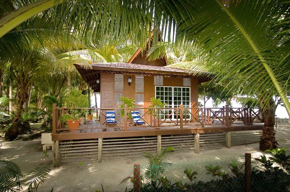 Suite Chalet with a sun deck on the sand under palm trees at Sipadan-Mabul Resort