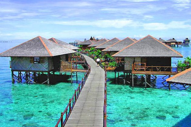 Timber boardwalk between thatched over-water chalets at Sipadan Water Village